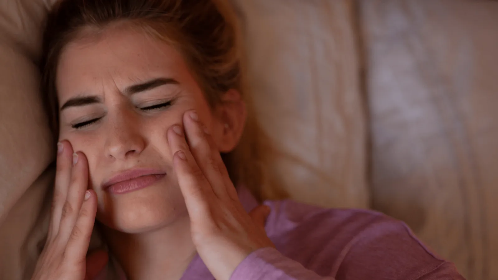 Stressed patient rubbing jaw, illustrating how seasonal stress impacts oral health