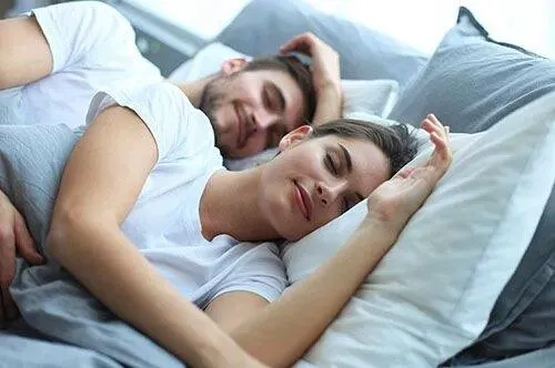 Happy couple sleeping comfortably in bed at home