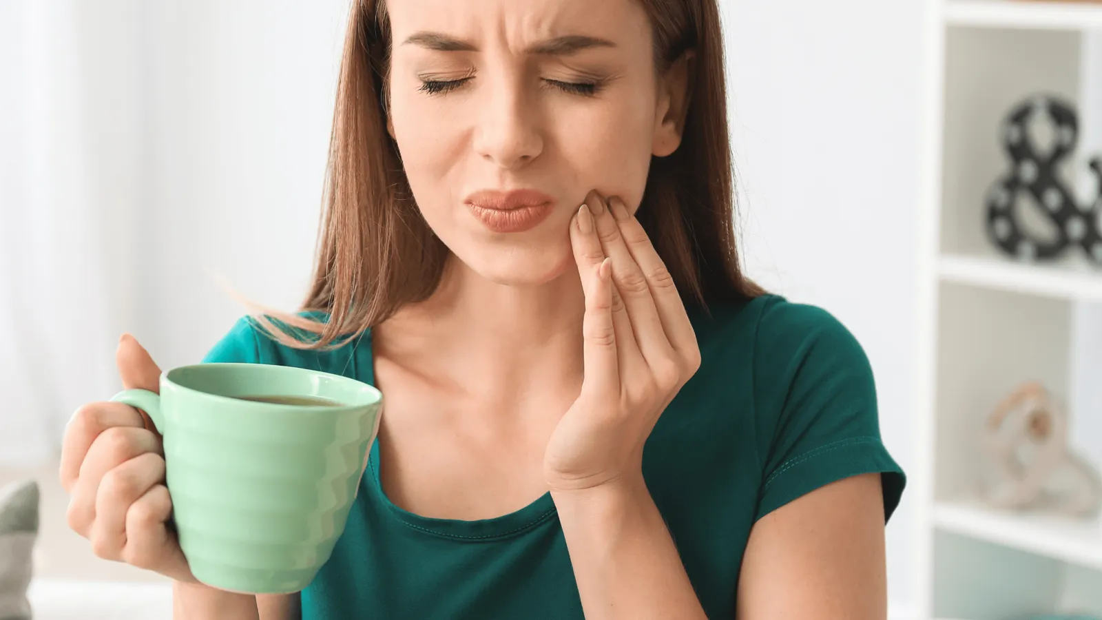 Woman feeling tooth sensitivity while enjoying a cold weather drink