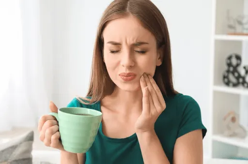 Woman experiencing tooth sensitivity while eating